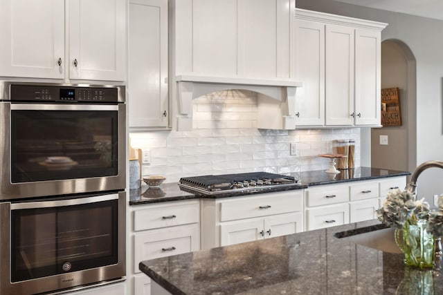 kitchen with sink, stainless steel appliances, tasteful backsplash, white cabinets, and dark stone counters