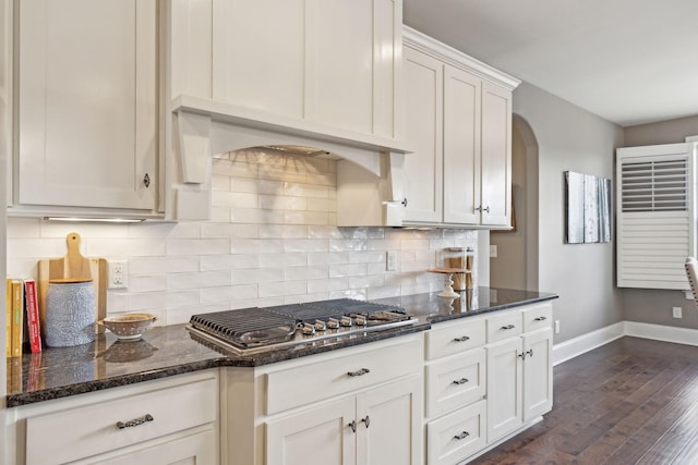 kitchen featuring dark wood-type flooring, white cabinetry, dark stone countertops, decorative backsplash, and stainless steel gas stovetop