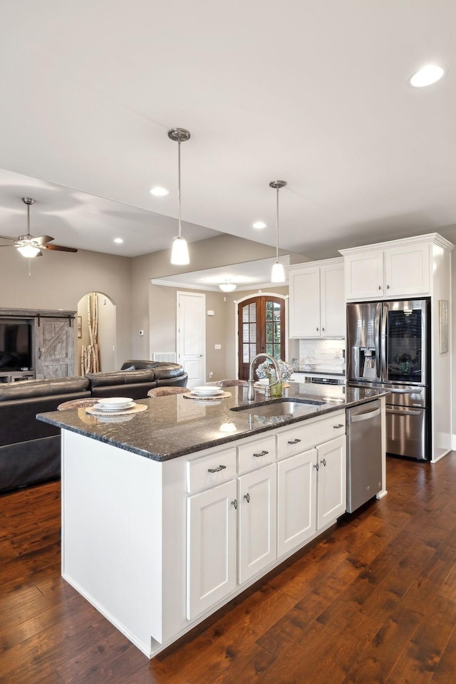 kitchen with appliances with stainless steel finishes, a kitchen island with sink, and white cabinets