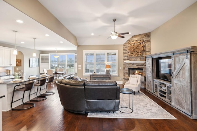 living room featuring ceiling fan, a barn door, lofted ceiling, and dark hardwood / wood-style flooring