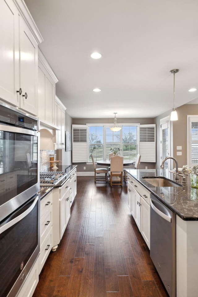 kitchen featuring pendant lighting, appliances with stainless steel finishes, sink, and white cabinets