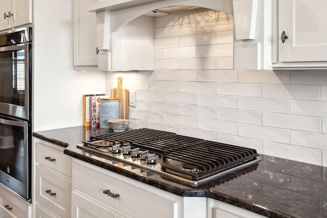 kitchen featuring dark stone counters, decorative backsplash, stainless steel gas cooktop, and white cabinets