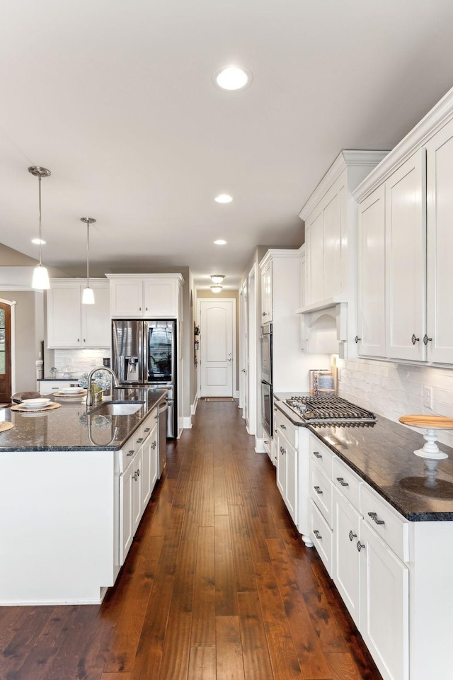 kitchen with decorative light fixtures, white cabinetry, sink, dark hardwood / wood-style flooring, and dark stone counters