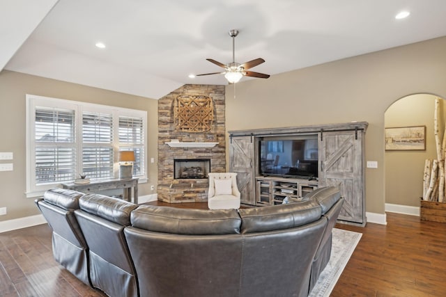 living room with ceiling fan, dark hardwood / wood-style flooring, vaulted ceiling, and a fireplace