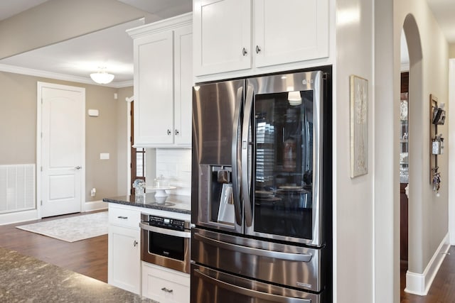 kitchen featuring dark wood-type flooring, dark stone counters, ornamental molding, stainless steel appliances, and white cabinets