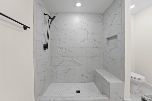 bathroom with a tile shower and toilet