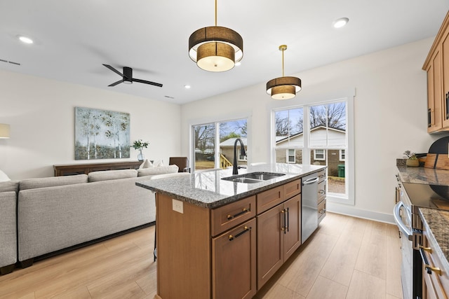 kitchen with sink, decorative light fixtures, a center island with sink, light wood-type flooring, and stainless steel appliances