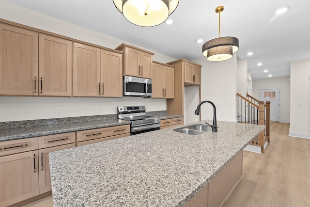 kitchen with sink, stainless steel appliances, a center island with sink, light wood-type flooring, and light brown cabinets