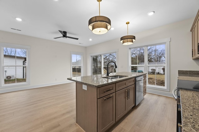 kitchen with sink, dark stone countertops, hanging light fixtures, stainless steel appliances, and light wood-type flooring