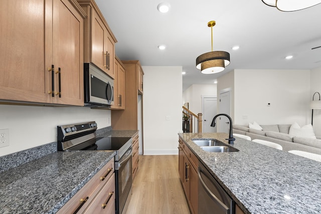 kitchen featuring decorative light fixtures, sink, dark stone counters, light hardwood / wood-style floors, and stainless steel appliances