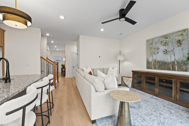 living room with sink, light hardwood / wood-style floors, and ceiling fan