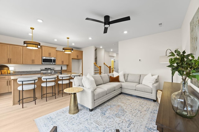 living room with ceiling fan, sink, and light wood-type flooring