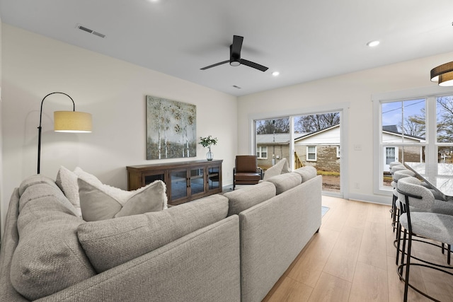 living room with ceiling fan, a healthy amount of sunlight, and light wood-type flooring