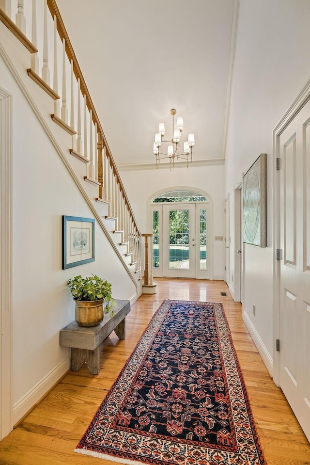 foyer featuring hardwood / wood-style flooring, ornamental molding, and an inviting chandelier