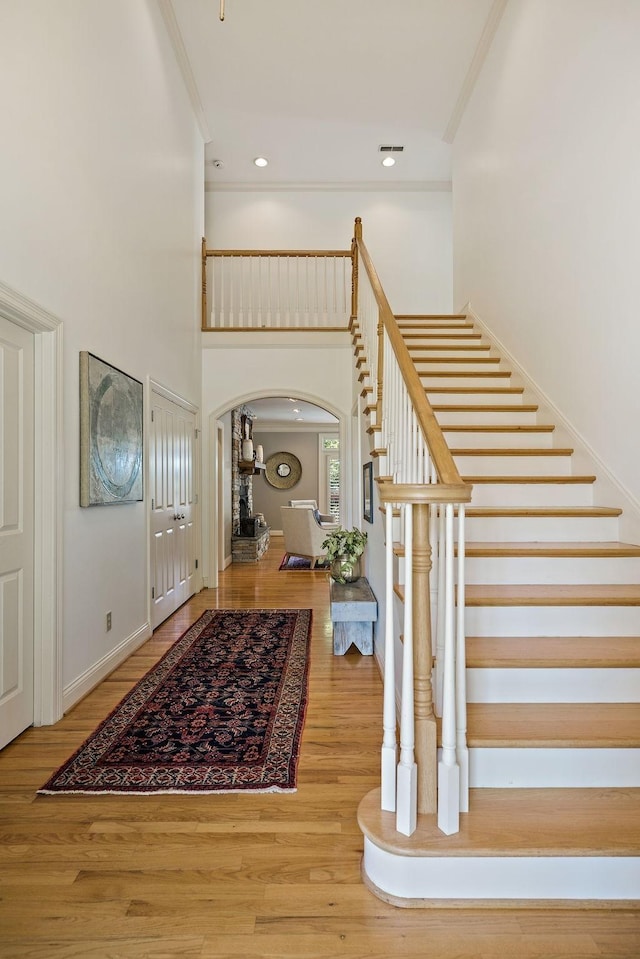 entrance foyer with crown molding, a towering ceiling, and wood-type flooring