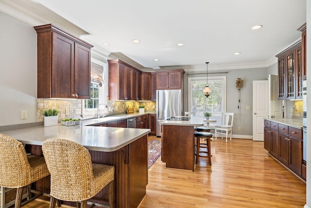 kitchen with a kitchen bar, stainless steel appliances, tasteful backsplash, a kitchen island, and decorative light fixtures