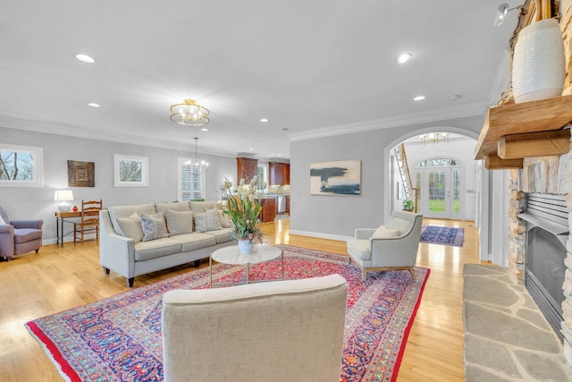 living room featuring crown molding, a fireplace, and a chandelier