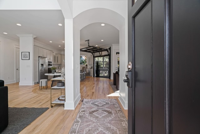 entryway with crown molding and light hardwood / wood-style flooring