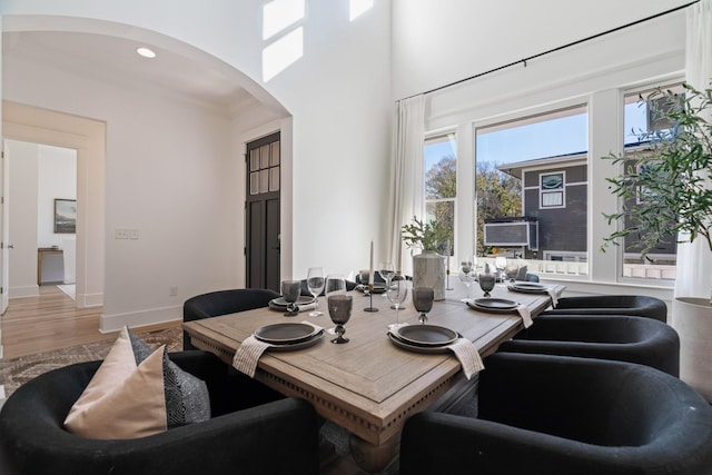 dining space featuring crown molding, hardwood / wood-style floors, and a high ceiling