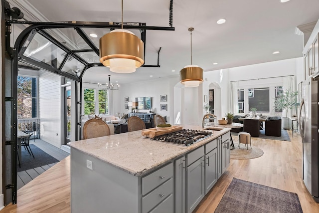 kitchen featuring decorative light fixtures, a kitchen island, light stone countertops, and appliances with stainless steel finishes