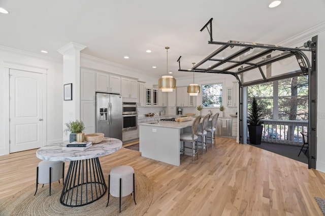 kitchen featuring a breakfast bar area, stainless steel appliances, a center island, light stone countertops, and decorative light fixtures