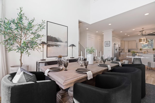 dining area with crown molding, ornate columns, and hardwood / wood-style flooring