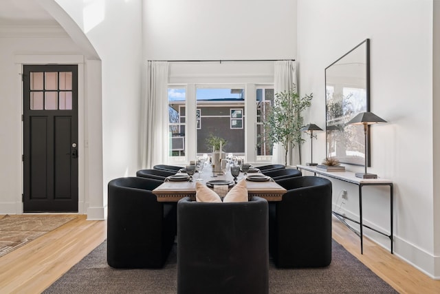 dining room with hardwood / wood-style flooring, a towering ceiling, and crown molding