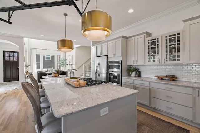 kitchen with pendant lighting, stainless steel appliances, a kitchen breakfast bar, light stone countertops, and a kitchen island