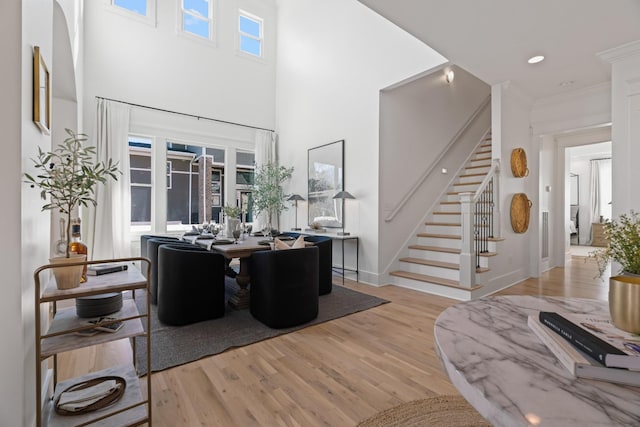 living room with crown molding, light hardwood / wood-style flooring, and a high ceiling