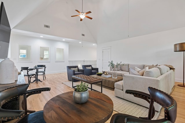 living room featuring light hardwood / wood-style flooring, high vaulted ceiling, and ceiling fan