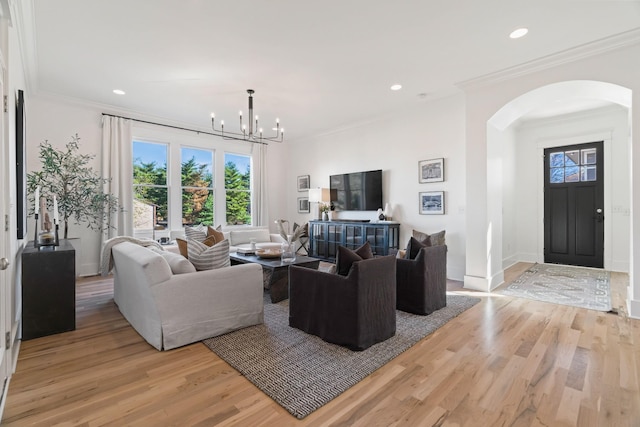 living room featuring crown molding, plenty of natural light, a chandelier, and light hardwood / wood-style flooring