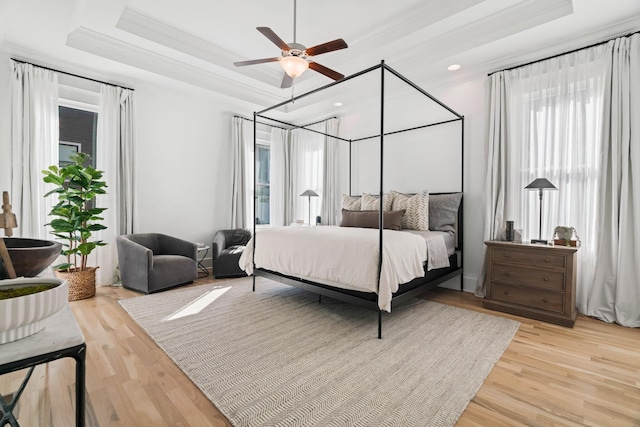 bedroom featuring ornamental molding, a tray ceiling, and multiple windows