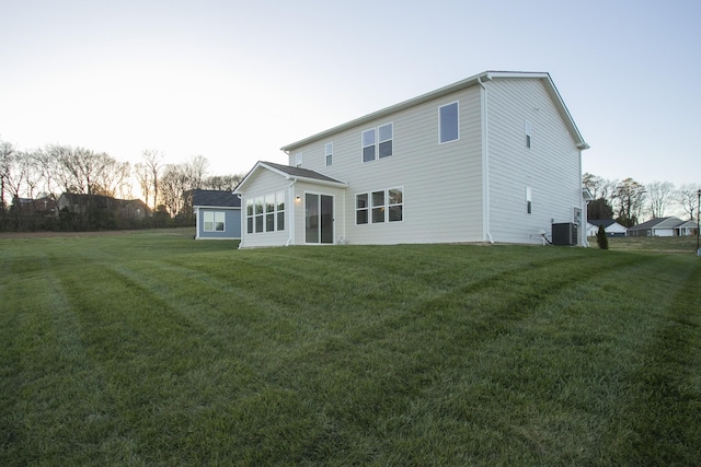 back house at dusk featuring cooling unit and a yard