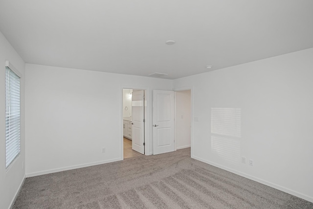 unfurnished bedroom with connected bathroom and light colored carpet