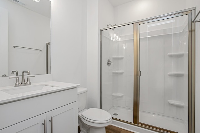 bathroom featuring vanity, hardwood / wood-style flooring, a shower with door, and toilet