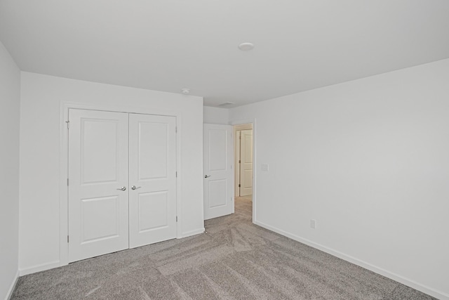 unfurnished bedroom featuring light colored carpet and a closet