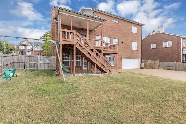 rear view of house featuring ceiling fan, a garage, a deck, and a lawn