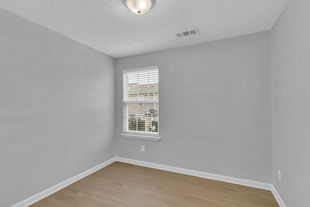 empty room featuring wood-type flooring and a textured ceiling