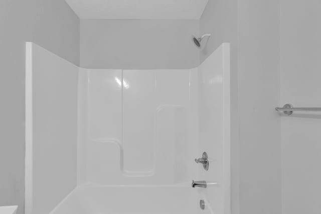 bathroom with bathing tub / shower combination and a textured ceiling