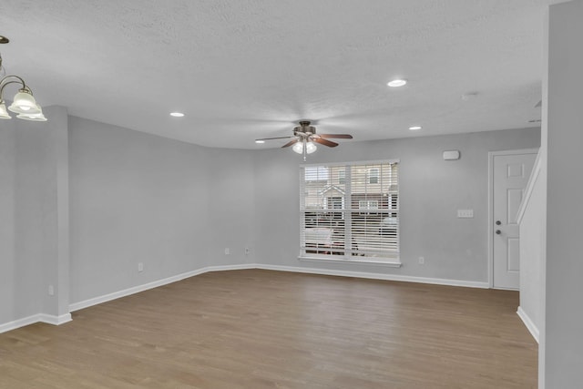 empty room featuring ceiling fan with notable chandelier, light hardwood / wood-style flooring, and a textured ceiling