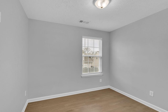 empty room with hardwood / wood-style floors and a textured ceiling