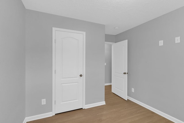 unfurnished bedroom with a textured ceiling and light hardwood / wood-style flooring