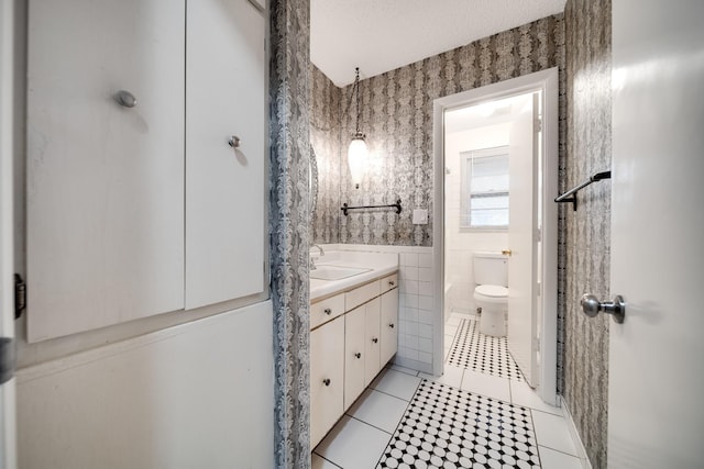 bathroom featuring toilet, tile walls, a textured ceiling, vanity, and tile patterned flooring