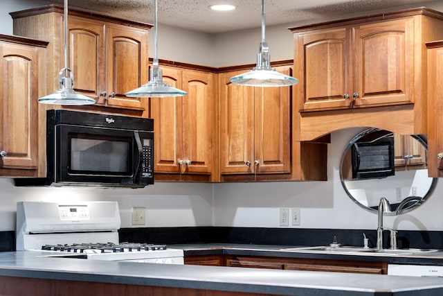 kitchen with pendant lighting, white appliances, sink, and a textured ceiling