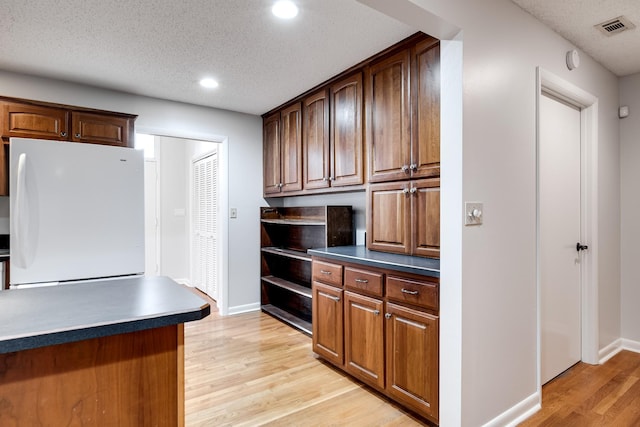 kitchen featuring white refrigerator, a textured ceiling, and light wood-type flooring