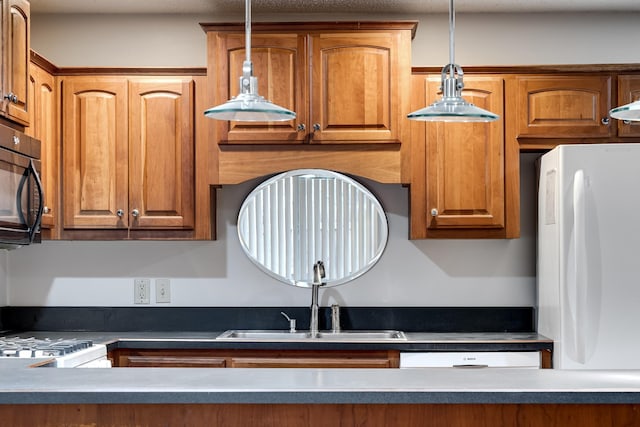 kitchen featuring sink, white appliances, and decorative light fixtures