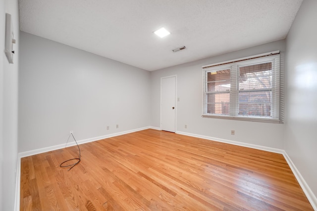 spare room featuring hardwood / wood-style flooring and a textured ceiling