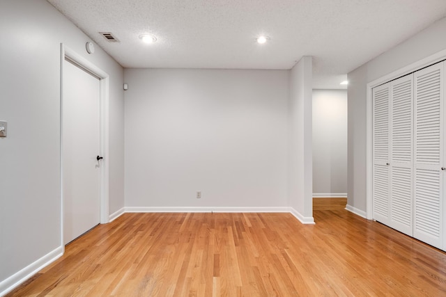 unfurnished bedroom with a textured ceiling, light wood-type flooring, and a closet