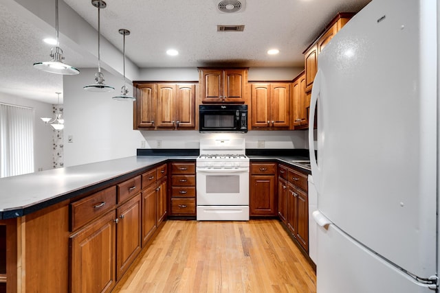 kitchen with pendant lighting, white appliances, light hardwood / wood-style floors, a textured ceiling, and kitchen peninsula