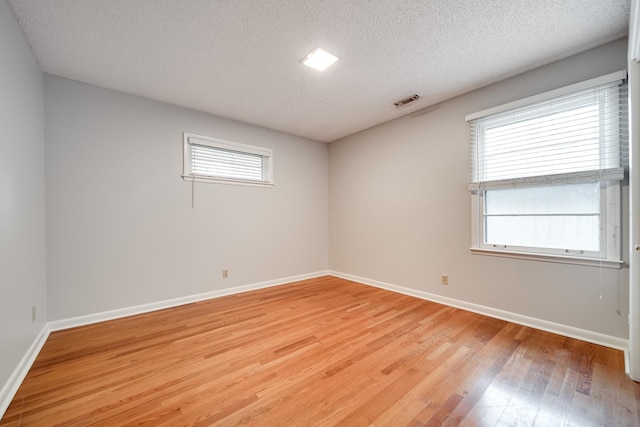 spare room with plenty of natural light, light hardwood / wood-style flooring, and a textured ceiling